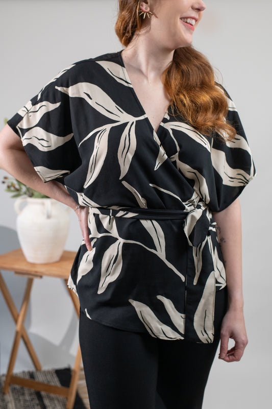 Woman wearing a black and white patterned top in a minimal indoor setting