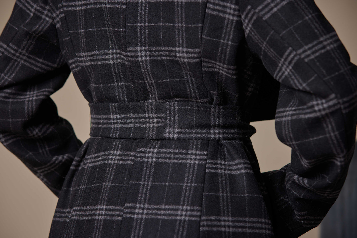 Dark plaid coat with a belt on a neutral background