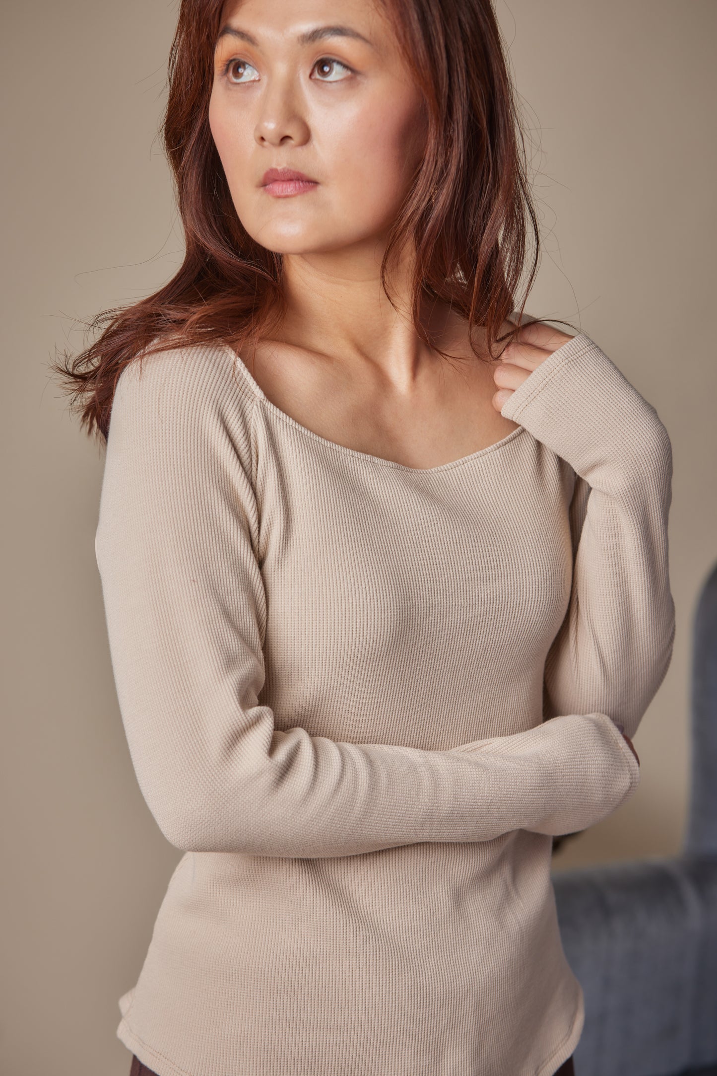 Woman wearing a beige sweater against a neutral background