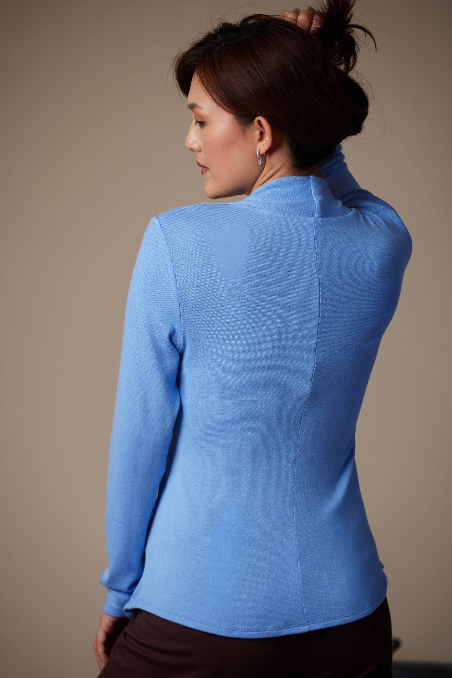 Woman wearing a blue long-sleeve top against a plain background