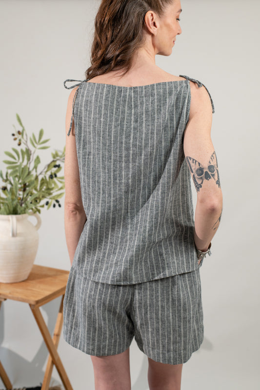 Woman wearing a gray striped outfit with a plant and table in the background