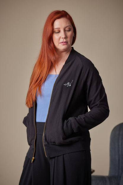 Woman wearing a black jacket with a logo on a beige background