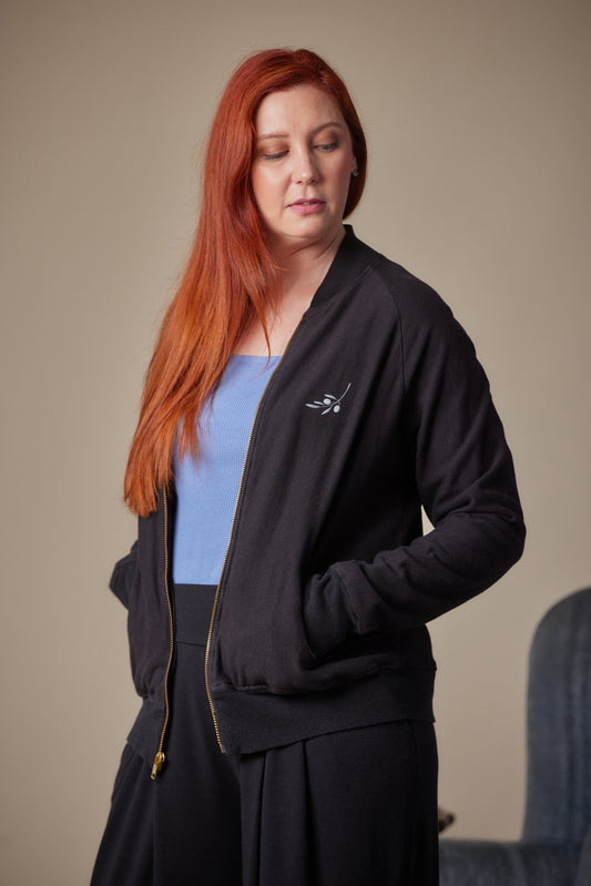 Woman wearing a black jacket with a logo on a beige background