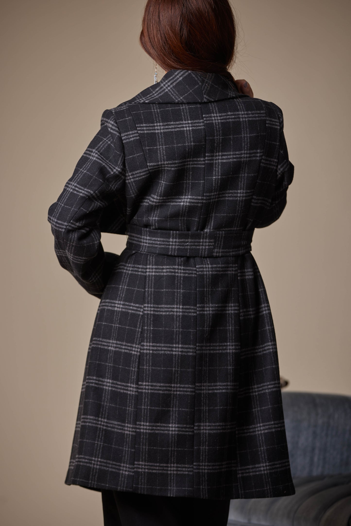 Person wearing a plaid coat against a neutral background