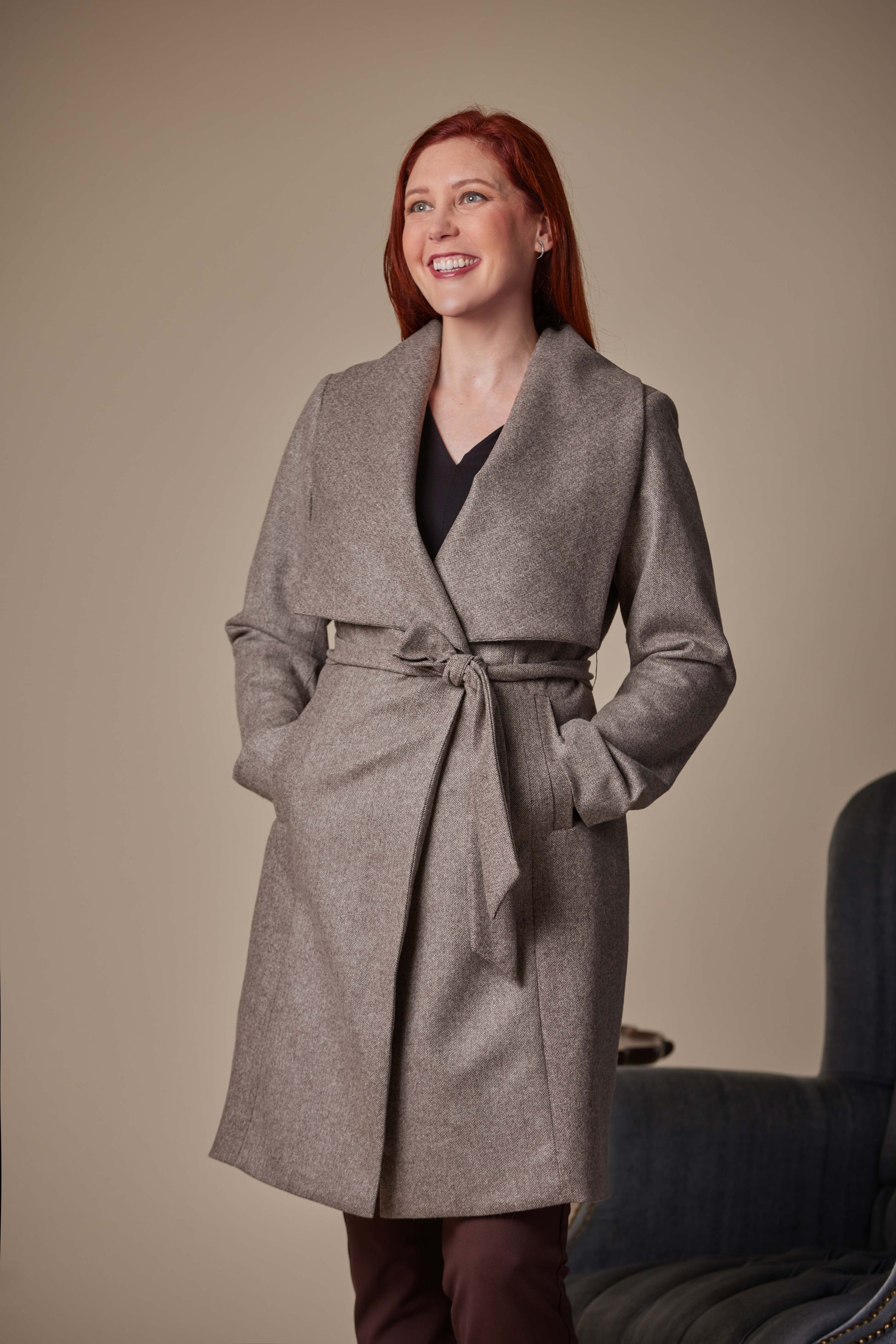 Woman wearing a gray coat against a beige background