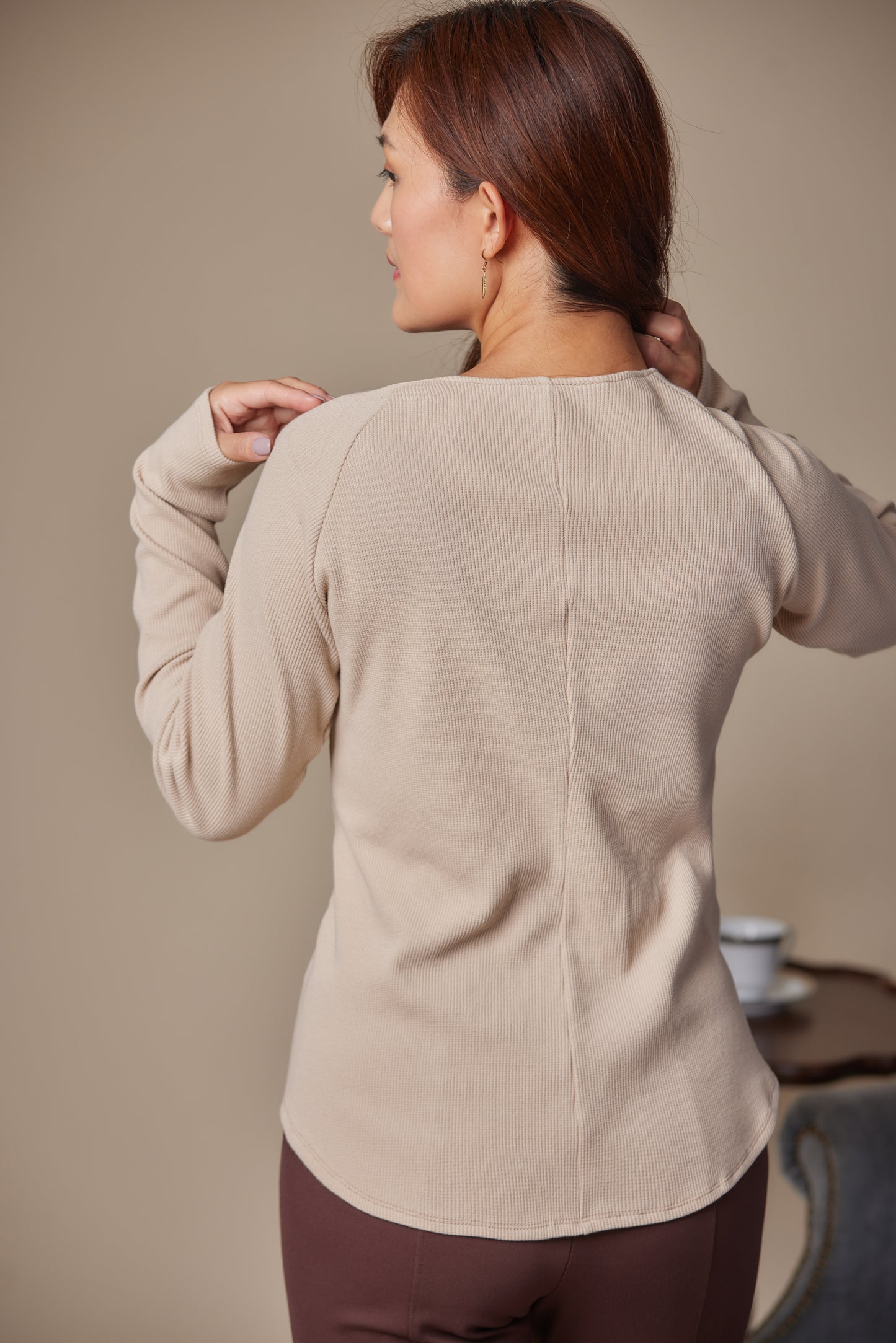 Woman wearing a beige sweater against a neutral background