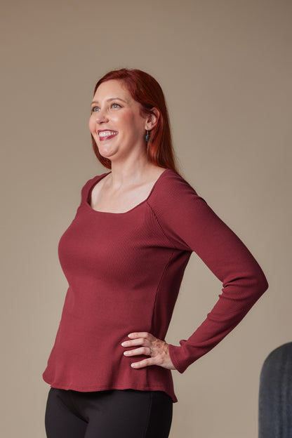 Woman wearing a red long-sleeve top against a beige background