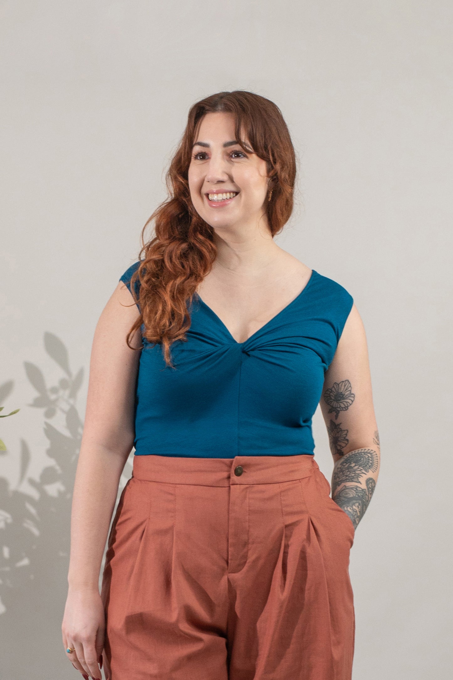 Woman wearing a blue top and brown pants against a plain background