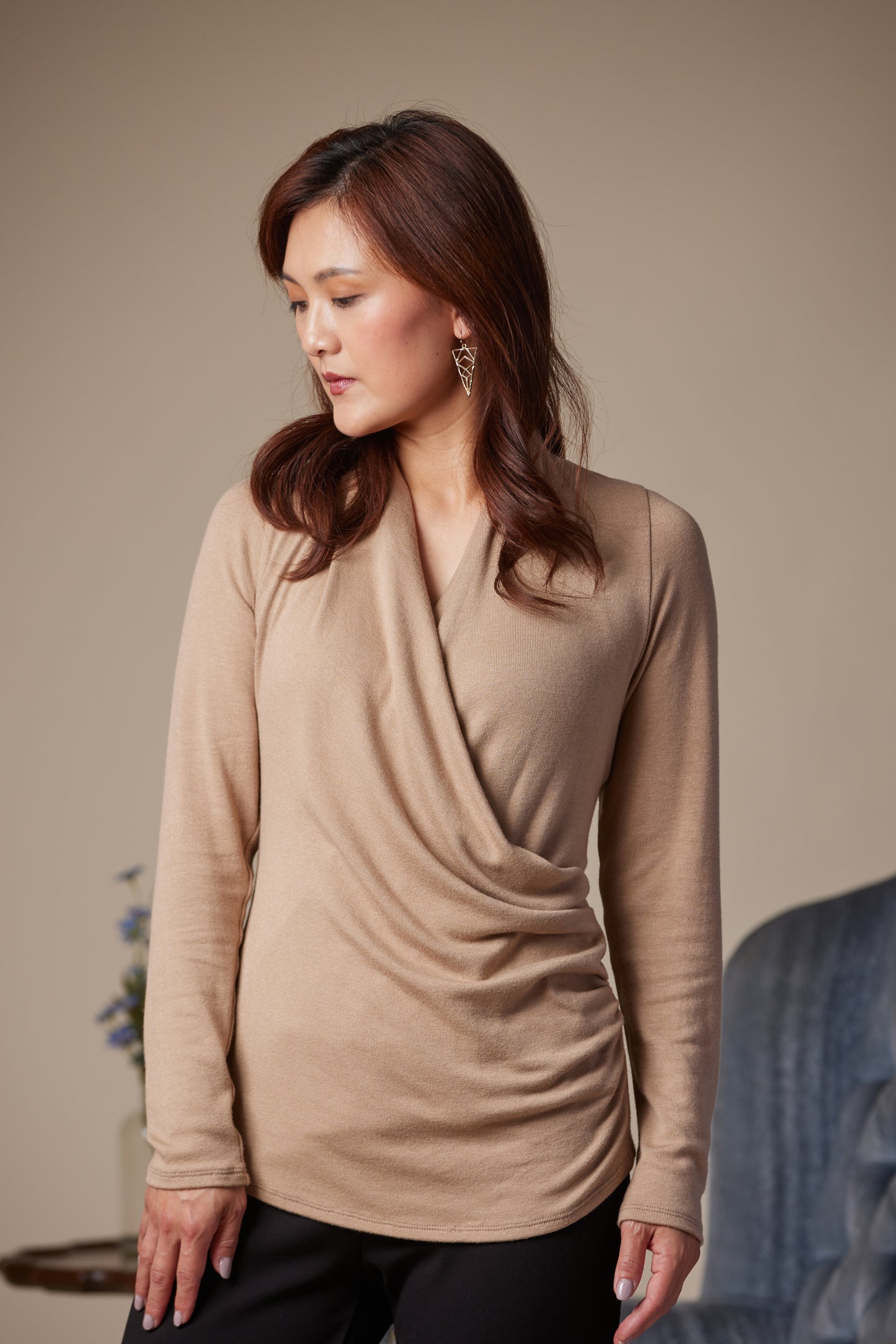 Woman wearing a beige long-sleeve top against a neutral background