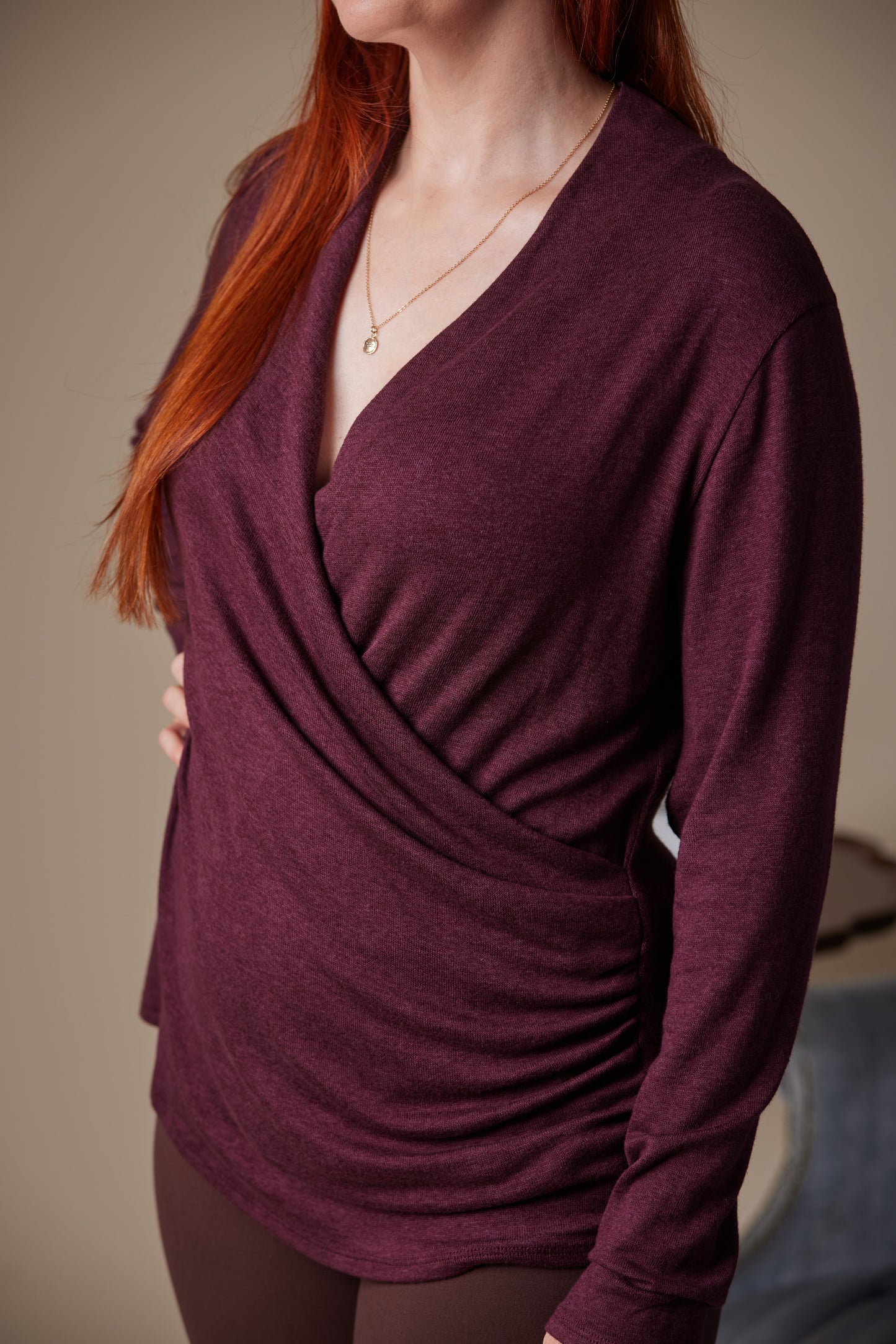 Woman wearing a burgundy long-sleeve top with a plain background