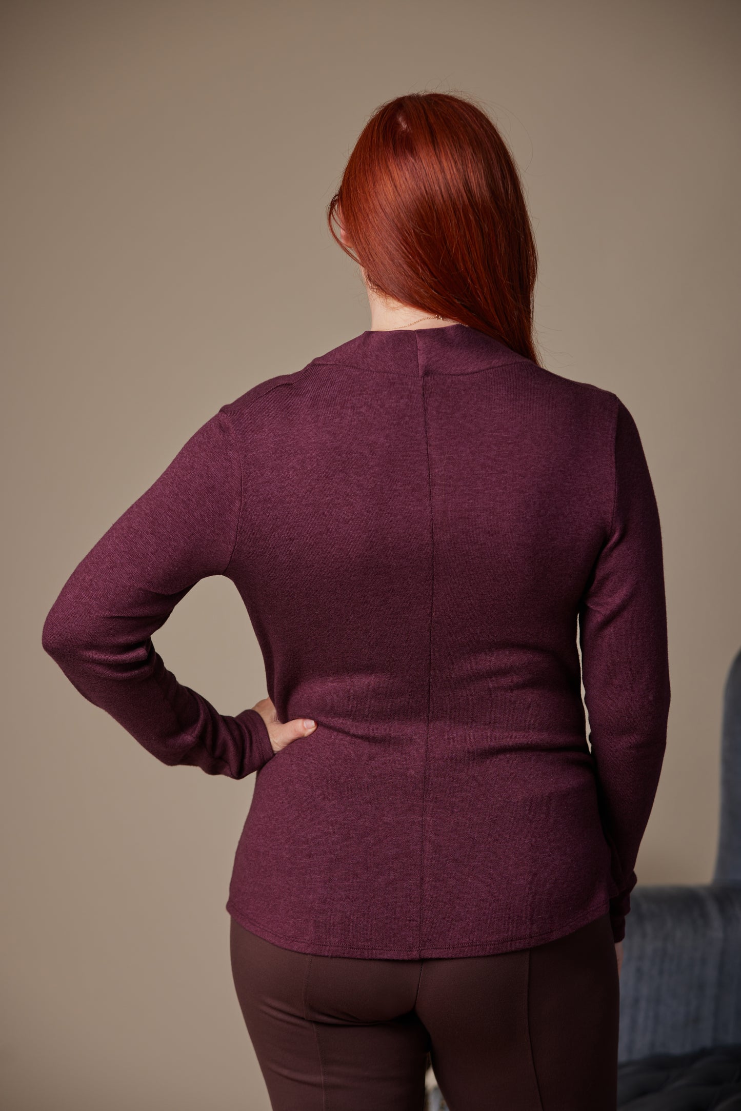 Person wearing a maroon long-sleeve top and pants against a neutral background