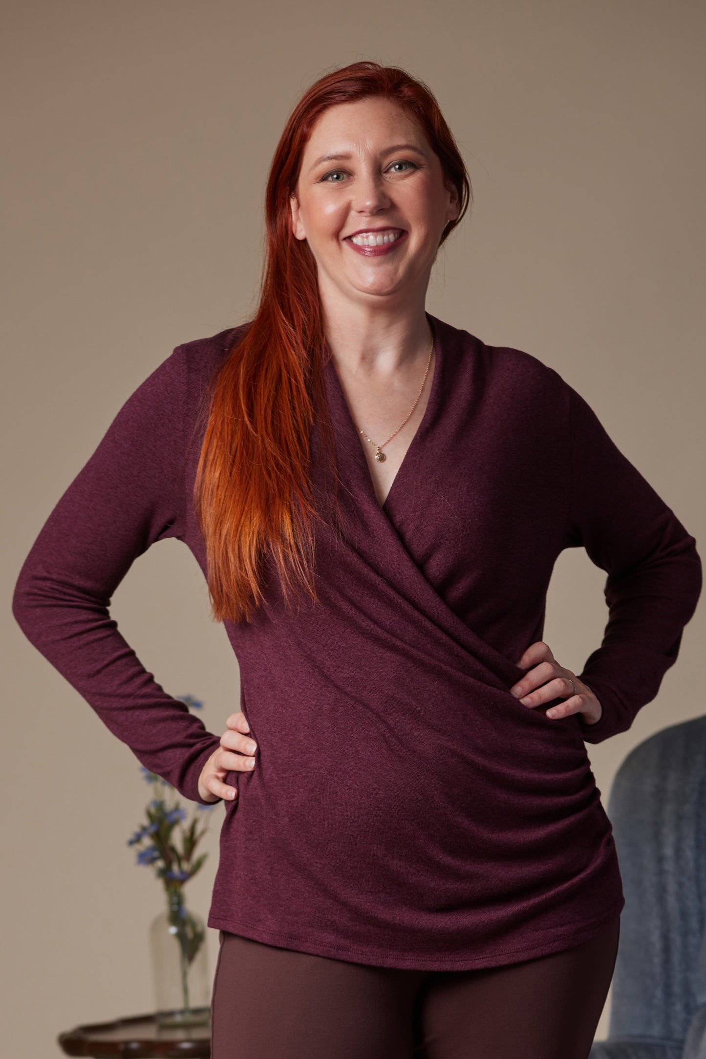 Woman wearing a maroon long-sleeve top with a neutral background