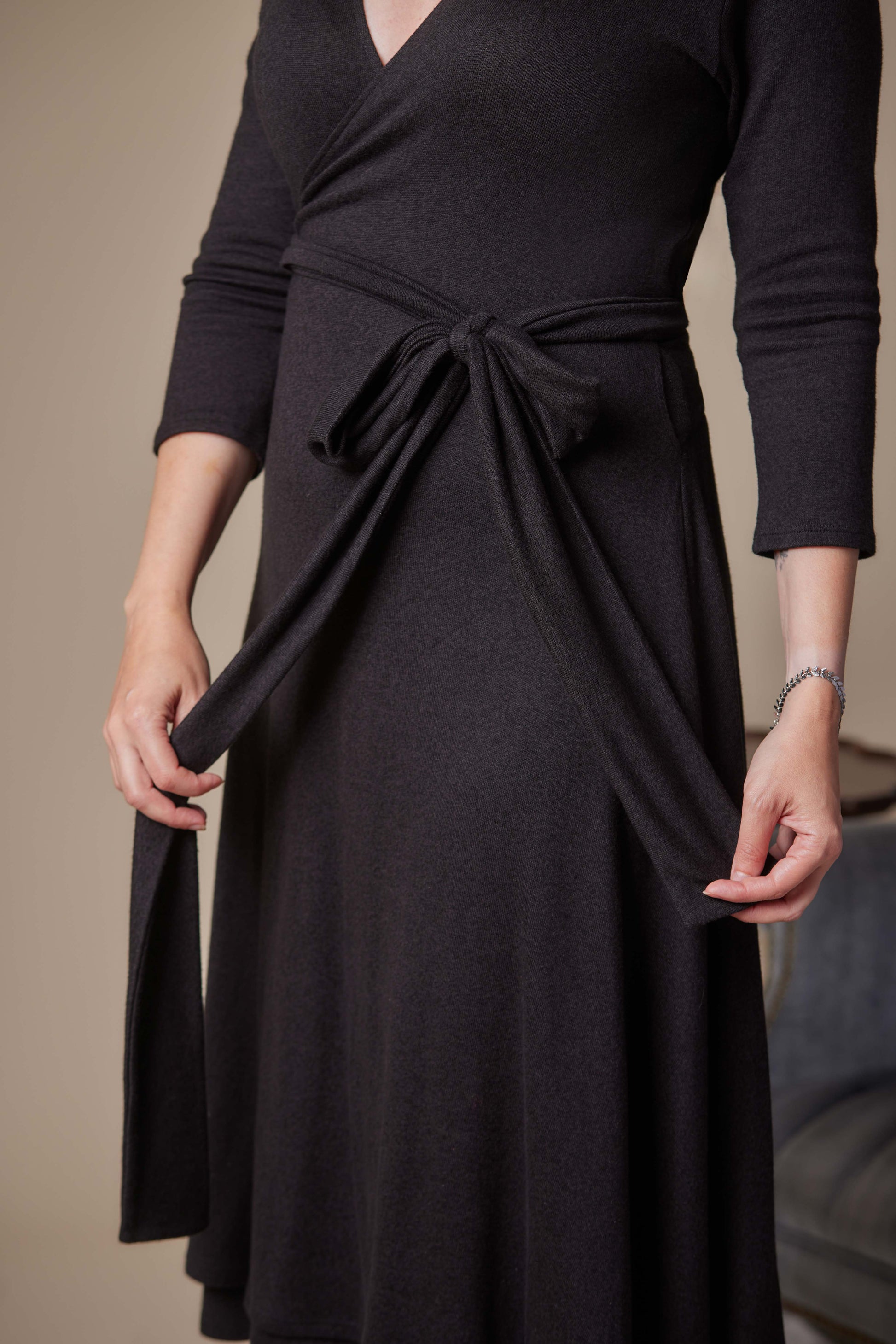 Black wrap dress with a tie waist worn by a person against a neutral background