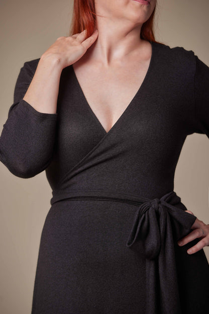 Woman wearing a black wrap dress against a neutral background