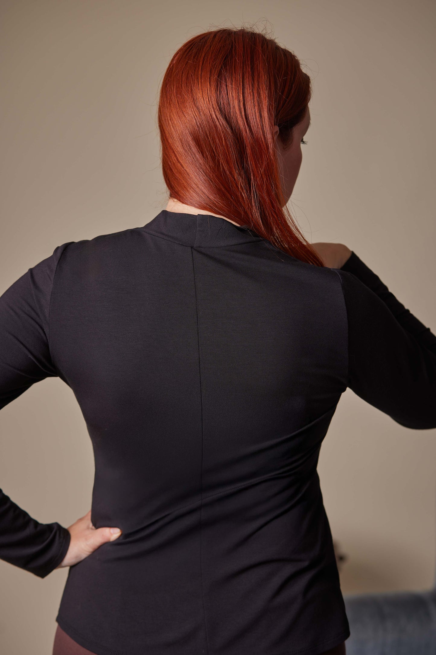Person wearing a black long-sleeve top with a neutral background