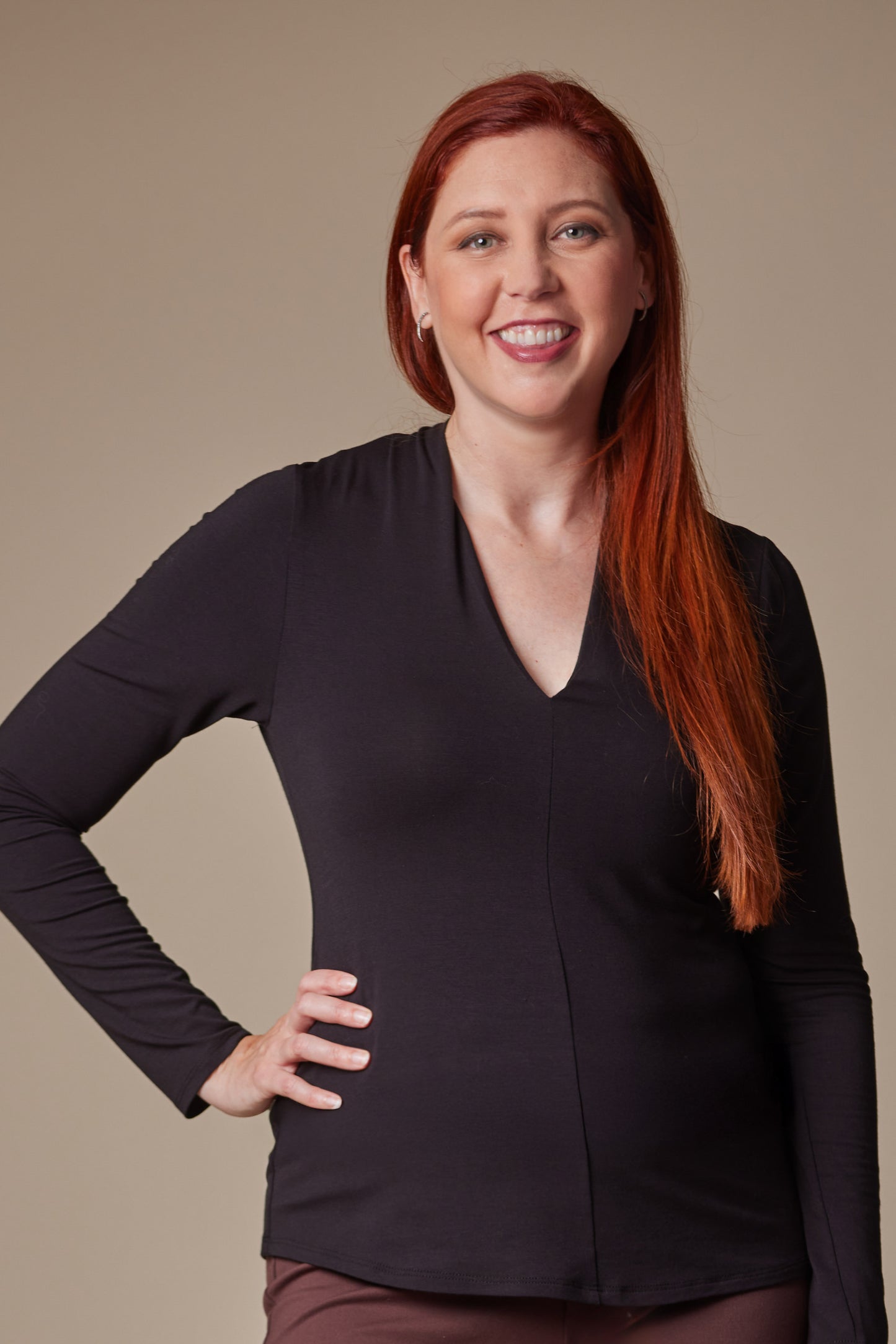 Woman wearing a black long-sleeve top against a beige background