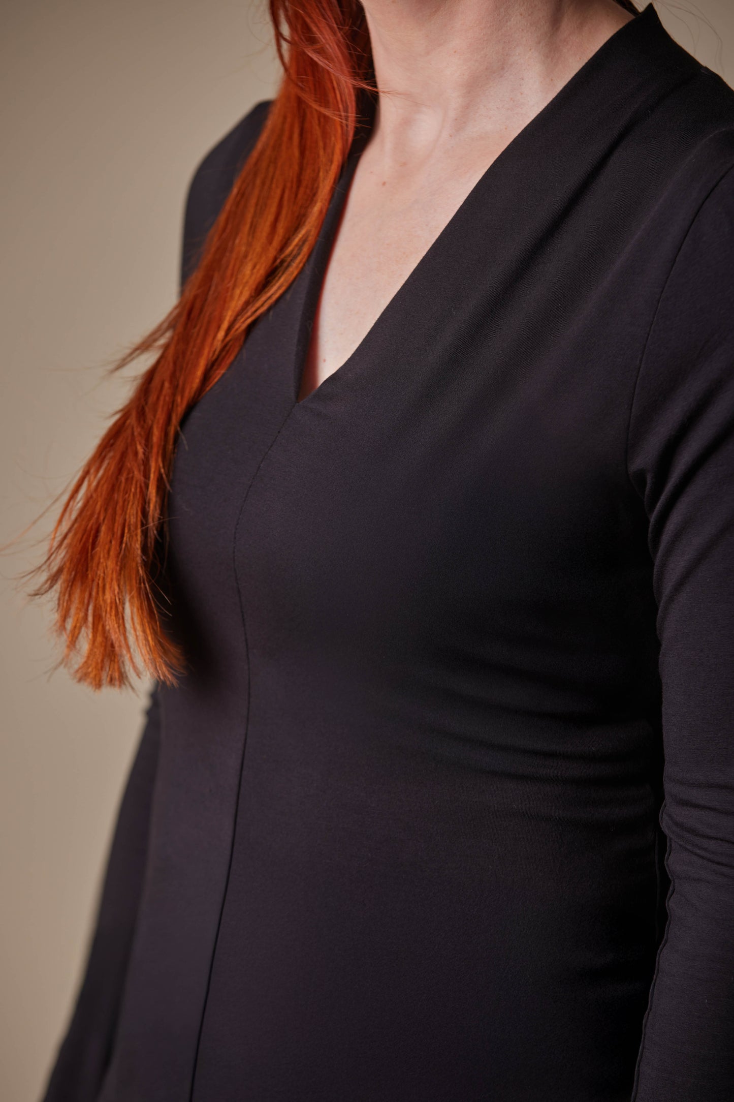 Person wearing a black long-sleeve top against a neutral background