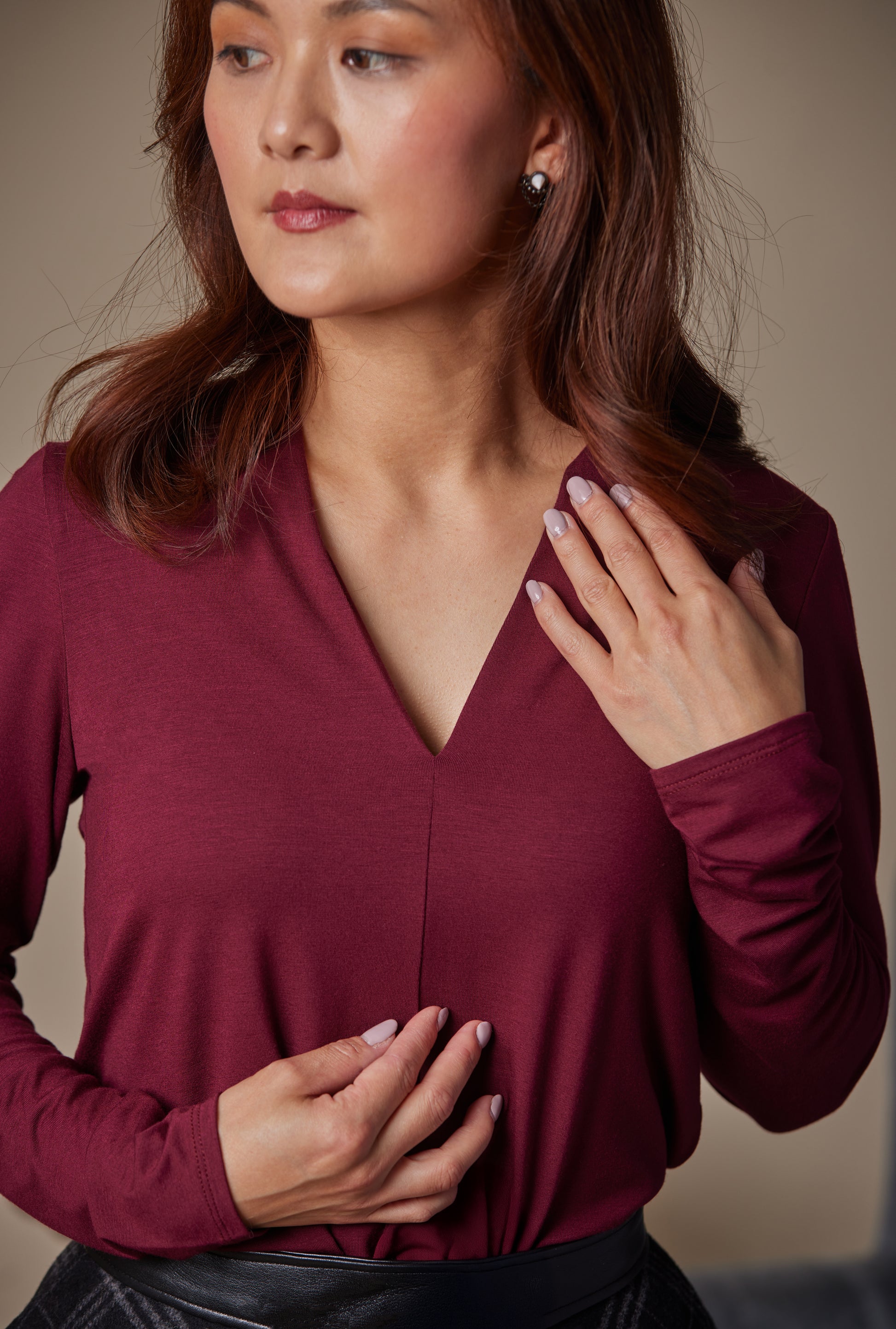 Woman wearing a burgundy long-sleeve top against a neutral background